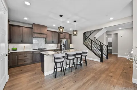a kitchen with stainless steel appliances kitchen island granite countertop a wooden floor and white cabinets