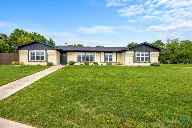 a view of a house with a big yard and large trees