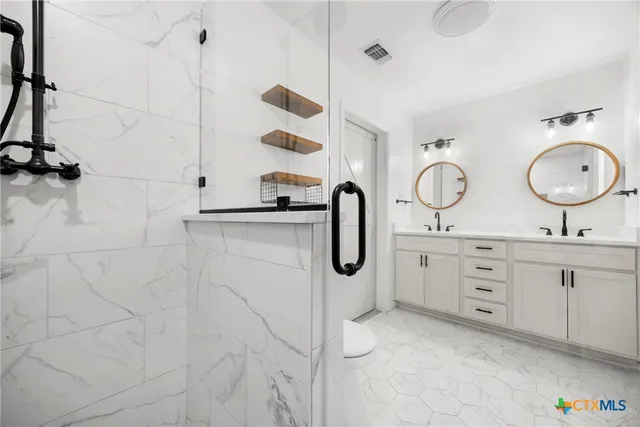 a bathroom with a double vanity sink mirror and shower