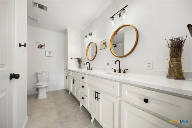 a bathroom with a double vanity sink mirror and toilet
