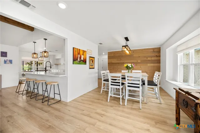 a dining room with furniture wooden floor a rug and a painting