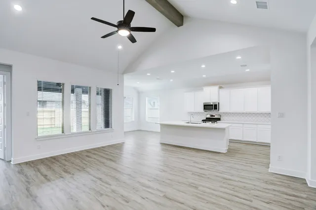 a view of kitchen with stainless steel appliances sink large window and wooden floor