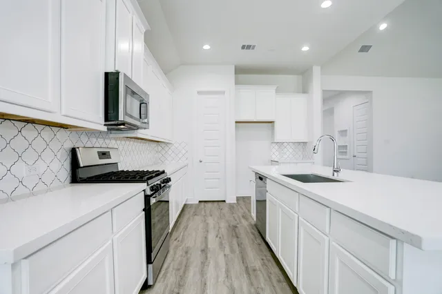 a kitchen with stainless steel appliances a sink stove and cabinets