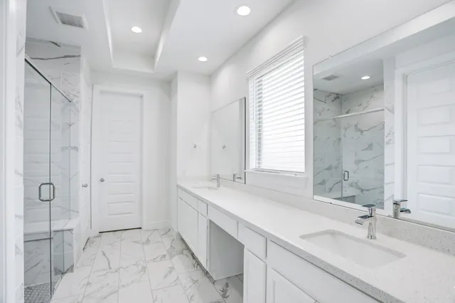 a bathroom with a double vanity sink mirror and shower