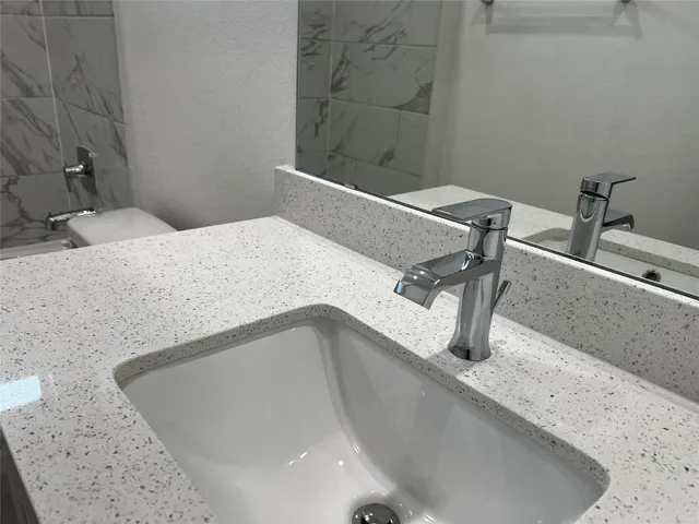a bathroom with a granite countertop sink a toilet and with tub