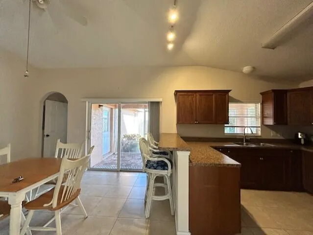 a kitchen with stainless steel appliances granite countertop a stove top oven a sink dishwasher a dining table and chairs with wooden floor