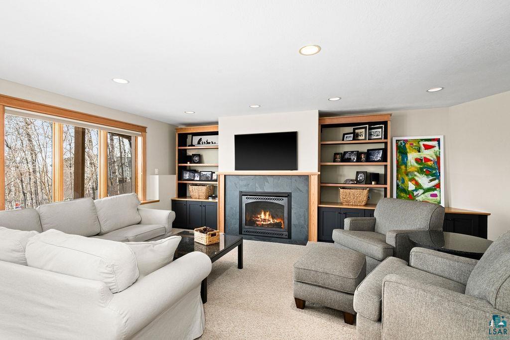 4856 Kingston Street Duluth, MN 55804 - Photo 42 of 88 Living area featuring a fireplace with a stone surround and wood mantel, flanked by built-in shelving and lower cabinetry