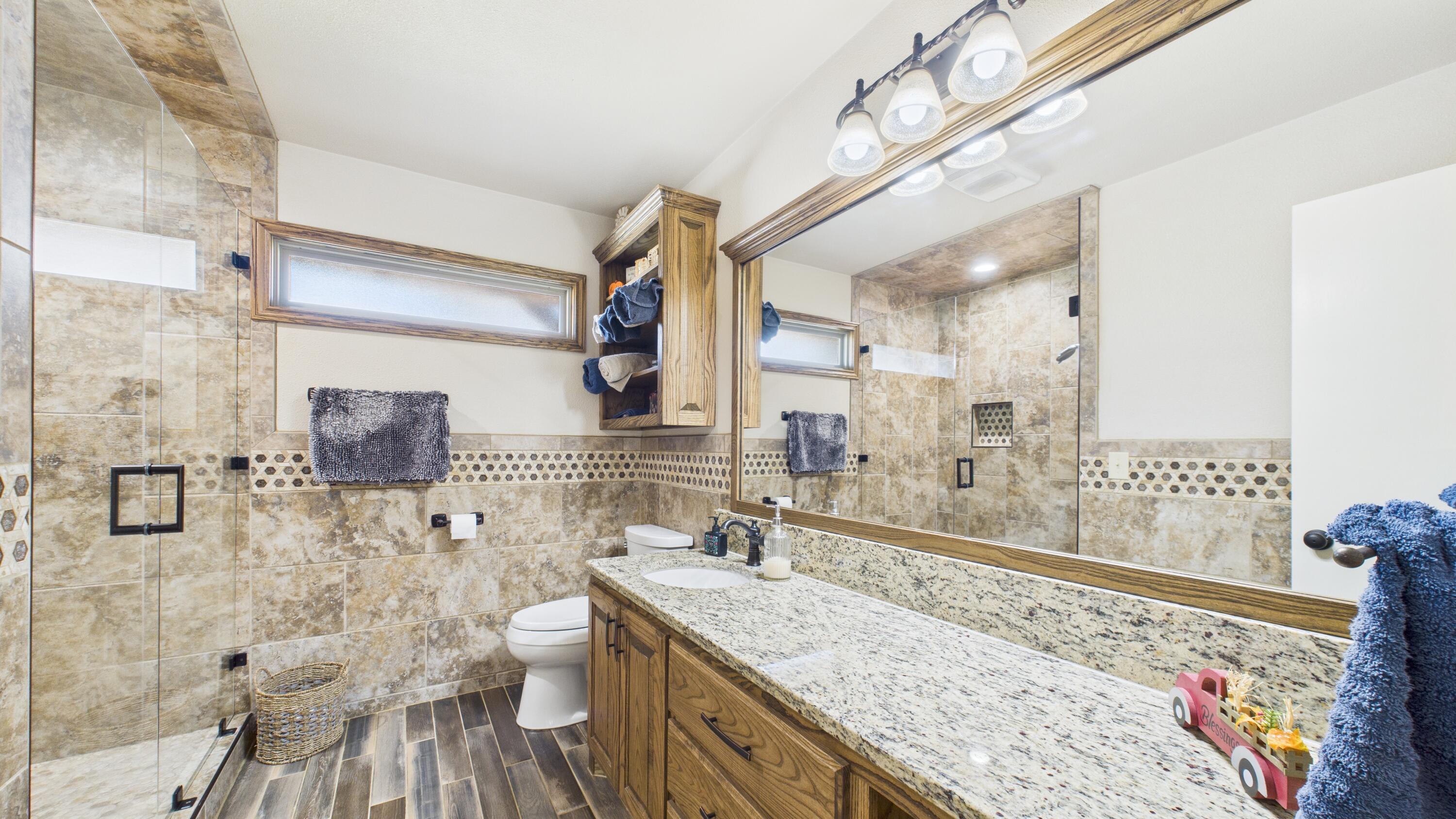 609 North 21st Street Lamesa, TX 79331 - Photo 35 of 50 a bathroom with a granite countertop sink a toilet a mirror and shower