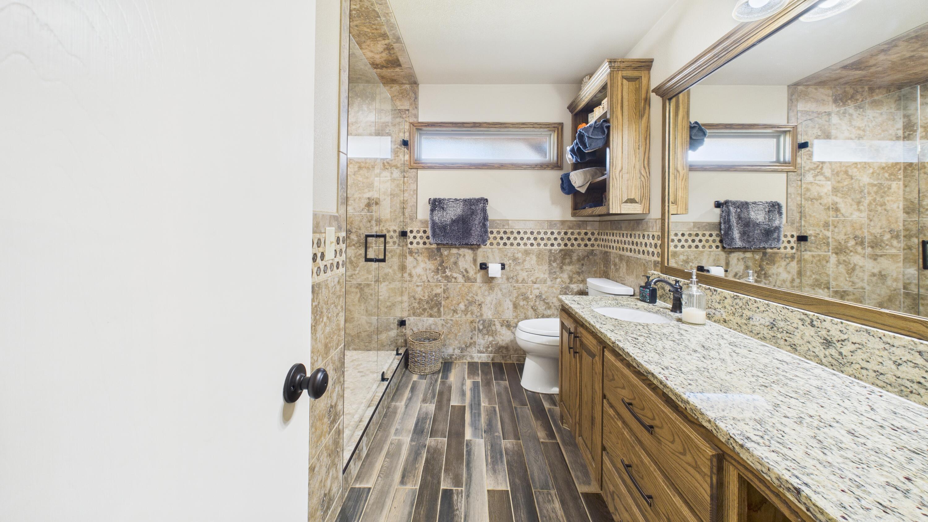 609 North 21st Street Lamesa, TX 79331 - Photo 38 of 50 a bathroom with a granite countertop sink a large mirror and a shower