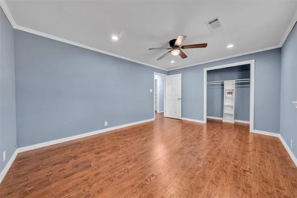 a view of empty room with wooden floor and ceiling fan