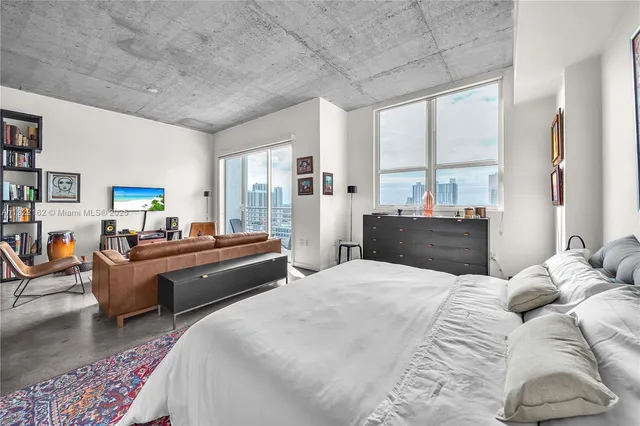 a bedroom with a bed couch and a large window