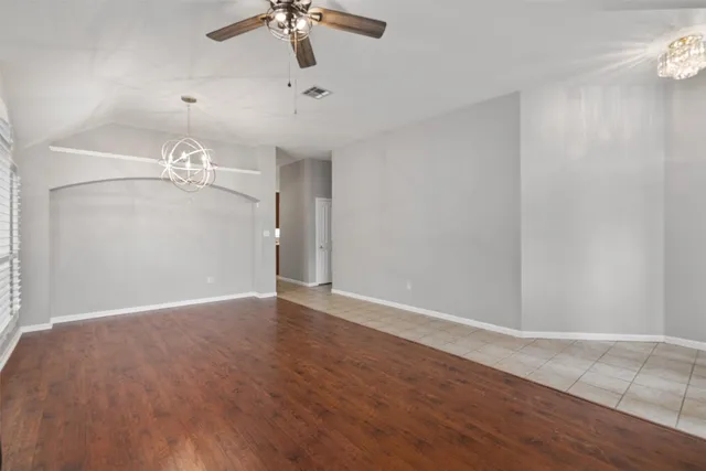 wooden floor in an empty room with a chandelier fan