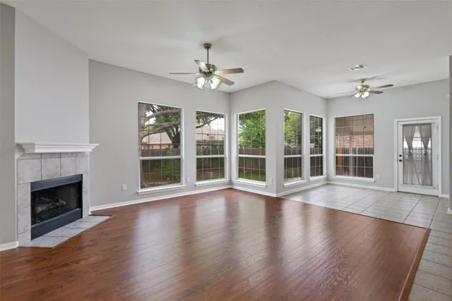 a view of an empty room with wooden floor and a fireplace