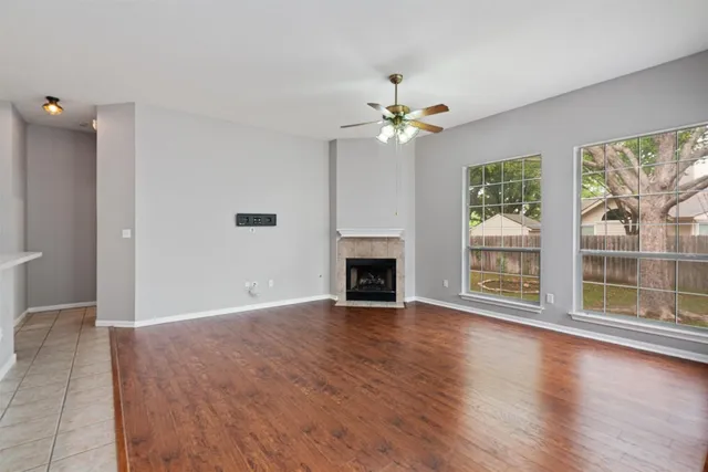 a view of an empty room with a window and wooden floor