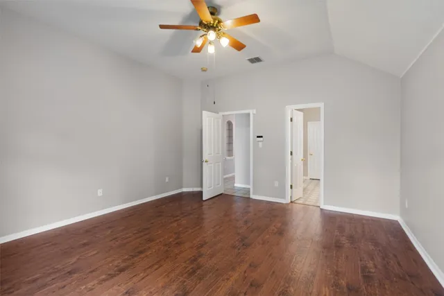 a view of an empty room with window a ceiling fan and wooden floor