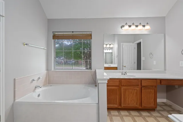 a bathroom with a tub a sink and mirror