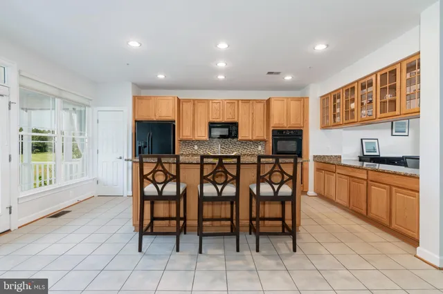 a kitchen with granite countertop a stove a sink a dining table and chairs