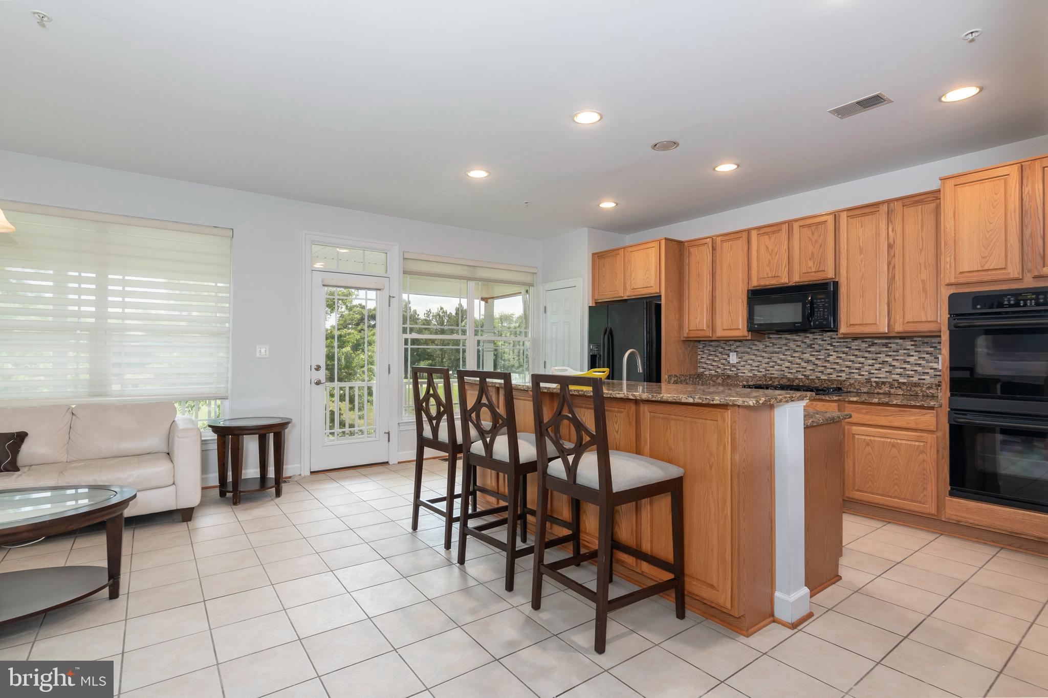 2804 Persimmon Place, Unit D3 Cambridge, MD 21613 - Photo 17 of 49 a kitchen with granite countertop a stove a sink a dining table and chairs