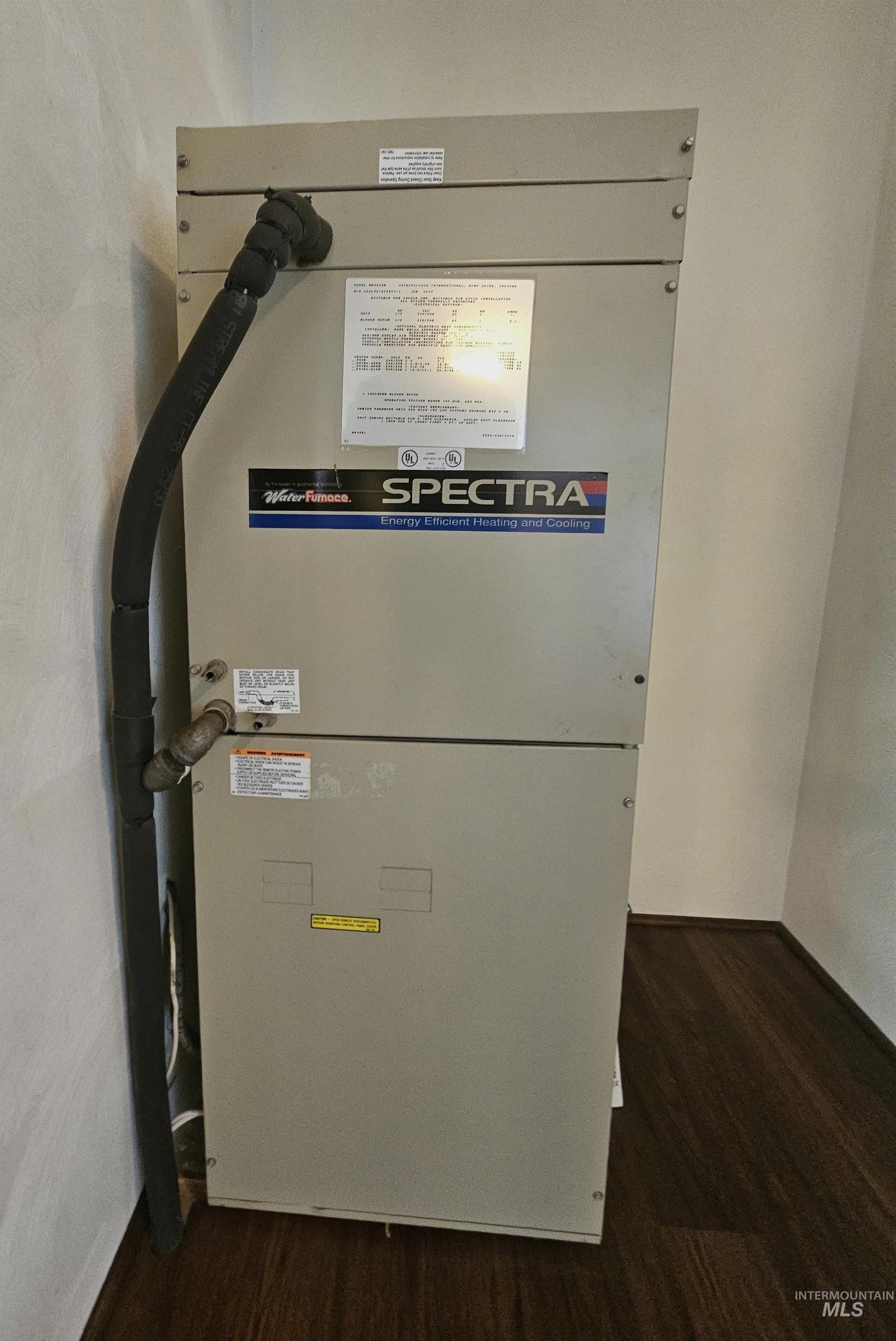 29865 Mission Creek Road Culdesac, ID 83524 - Photo 32 of 43 SPECTRA heating and cooling unit with insulated refrigerant line, positioned against a light-toned wall and dark wood-finish paneling
