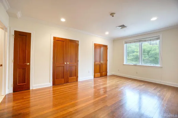 a view of an empty room with wooden floor and windows