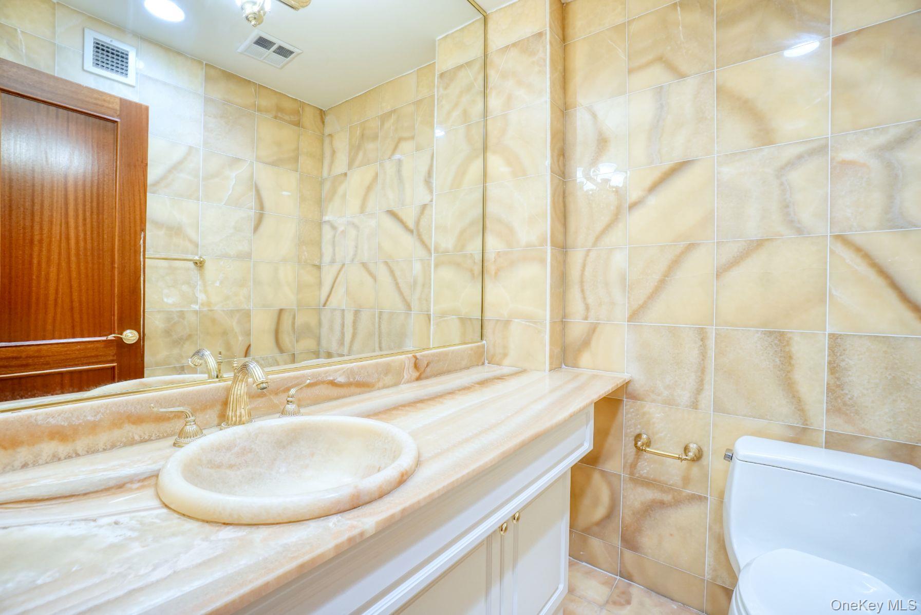 171 Great Neck Road, Unit 4L Great Neck, NY 11021 - Photo 10 of 15 Half bathroom with tile walls and vanity