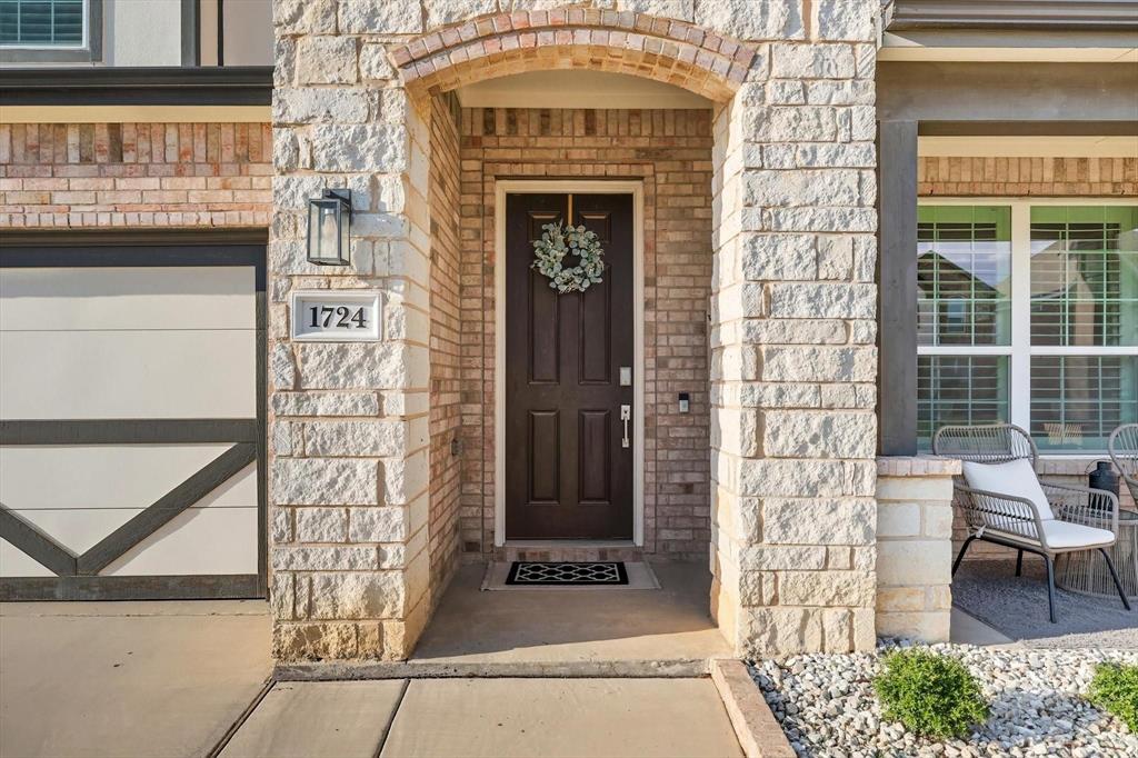 1724 Wassel Road Fort Worth, TX 76052 - Photo 2 of 24 Stone and brick façade with an arched entryway, dark panel door, and white frame windows