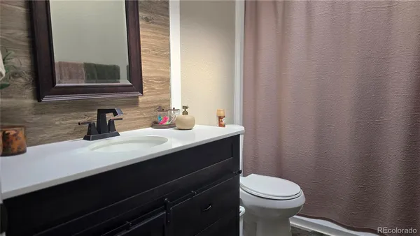 a bathroom with a sink a toilet a mirror and shower curtain