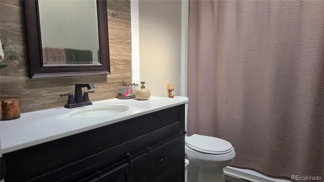 a bathroom with a sink a toilet a mirror and shower curtain