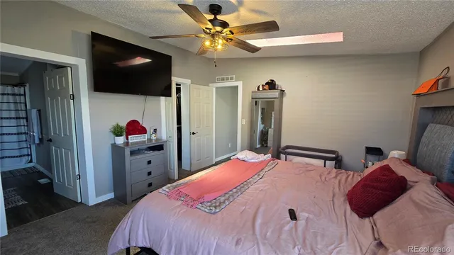 a bedroom with a bed and a flat tv screen on dresser