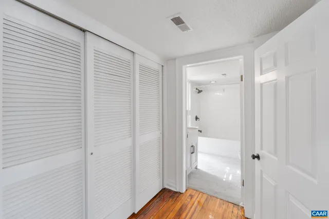 a view of empty room with wooden floor and fan