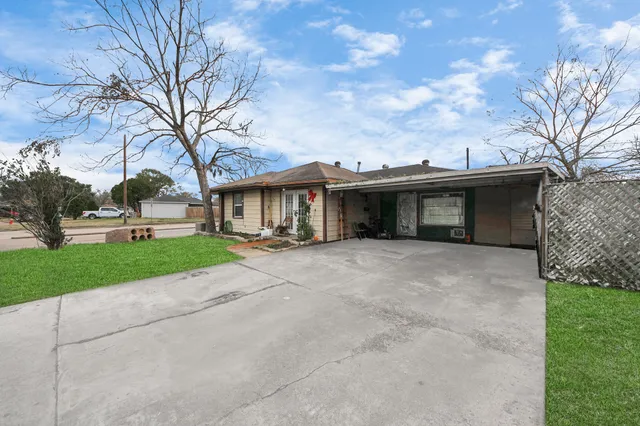 a view of a house with a yard and large tree