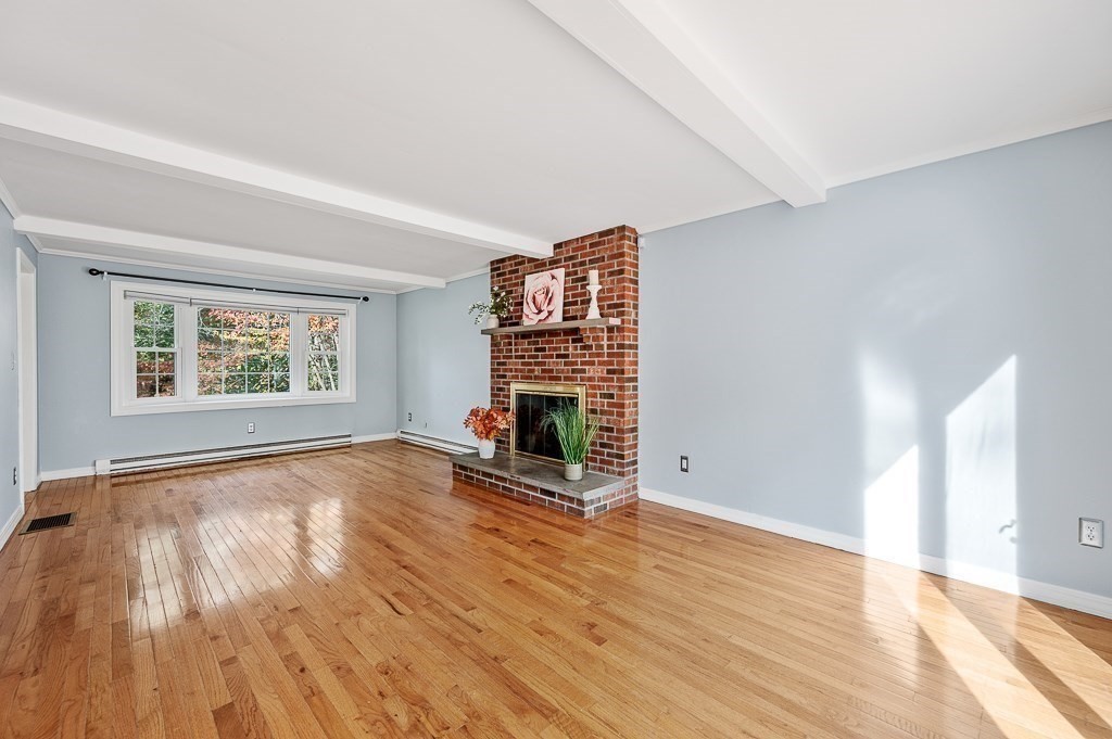 194 Paine Street Bellingham, MA 02019 - Photo 10 of 28 an empty room with wooden floor fireplace and windows