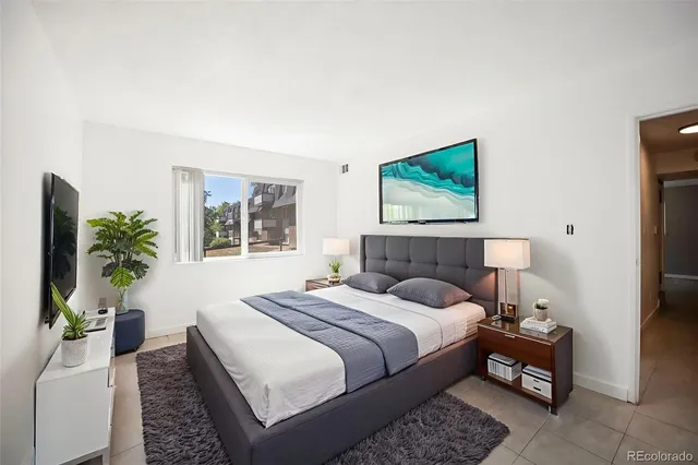 a bedroom with a bed a couch and potted plant