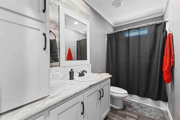 a bathroom with a sink a toilet and shower curtain