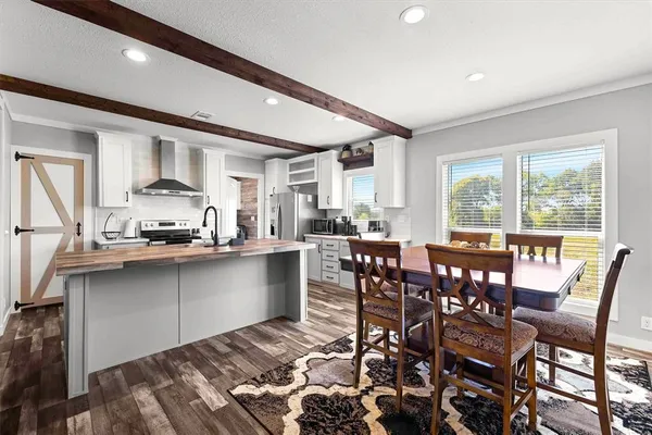 a dining hall with stainless steel appliances granite countertop a stove a sink a dining table and chairs