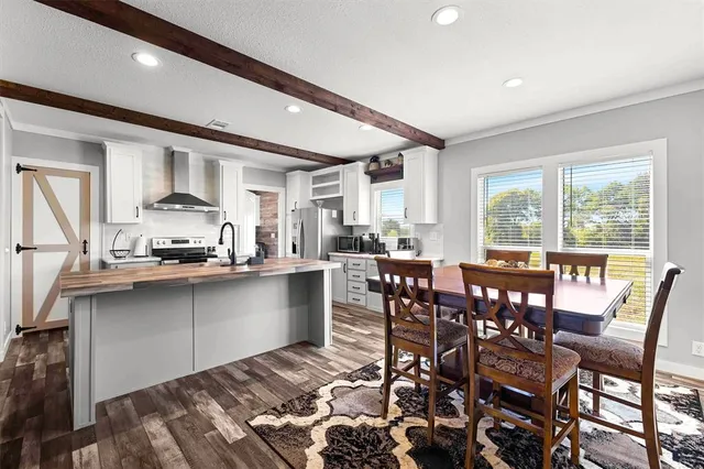 a dining hall with stainless steel appliances granite countertop a stove a sink a dining table and chairs