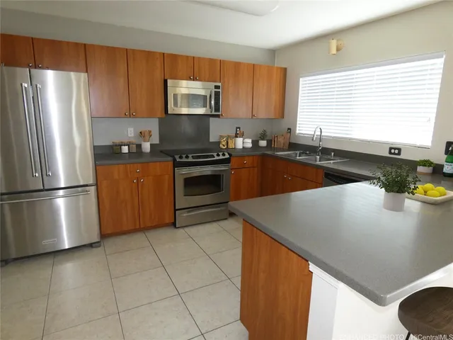 a kitchen with stainless steel appliances granite countertop a sink a stove a microwave a refrigerator a window