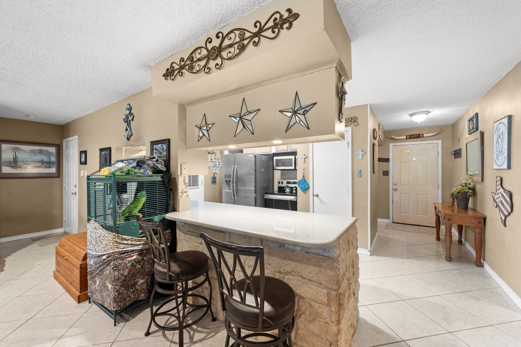 15602 Fir Road Santa Fe, TX 77517 - Photo 11 of 42 Spacious breakfast bar with stone accents and seating overlooks the open-concept living and kitchen areas, creating a welcoming space for casual dining and conversation. Ample counter space and an easy-flow layout enhance both functionality and entertaining potential.