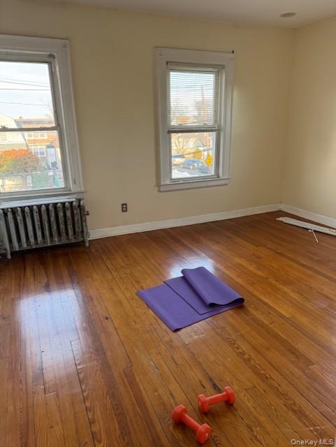 23-01 Enright Road Queens, NY 11691 - Photo 3 of 5 Spare room featuring radiator heating unit and dark wood-style flooring