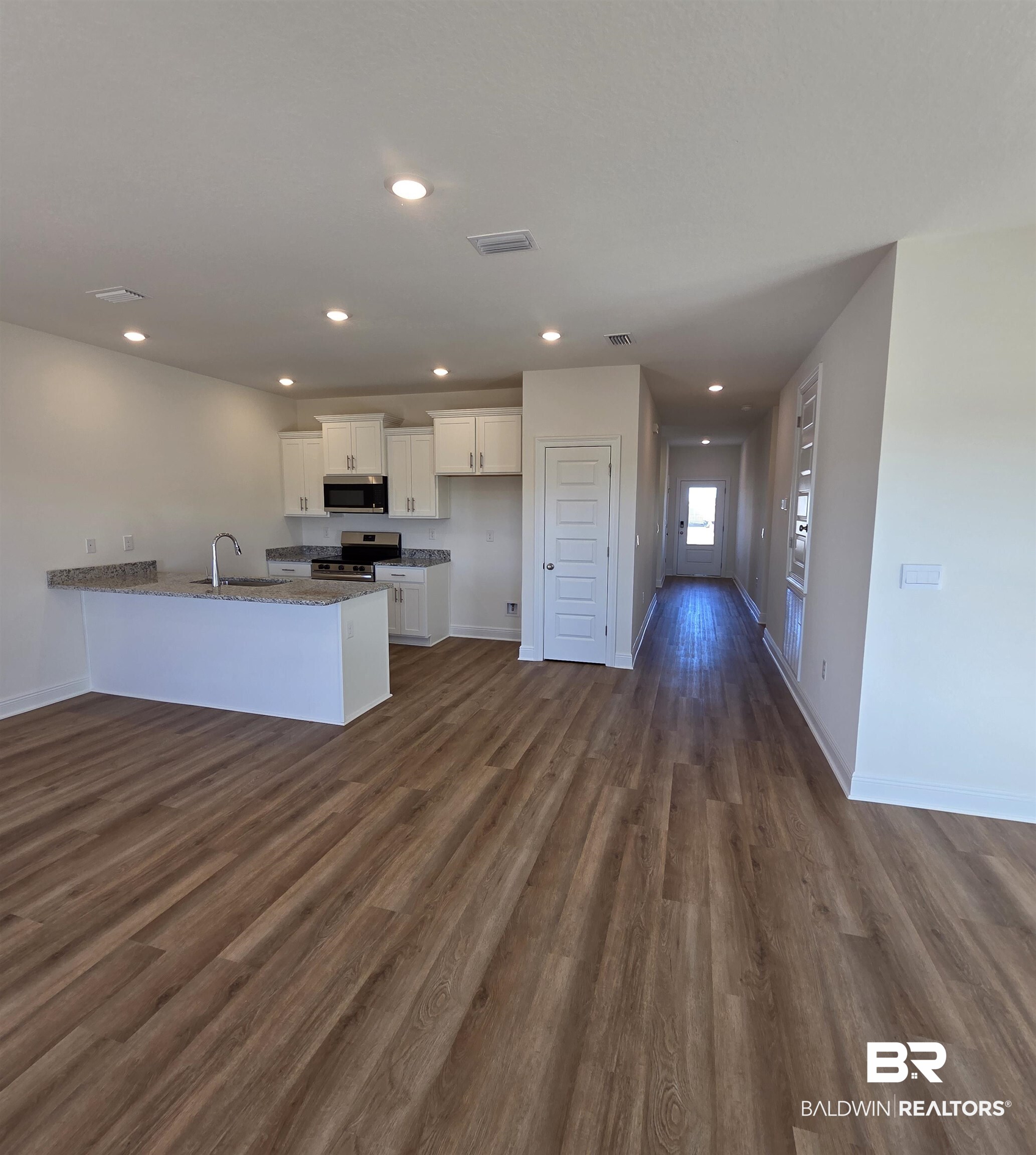 28084 Hallow Trail Elberta, AL 36530 - Photo 20 of 21 Kitchen featuring white cabinetry, a peninsula, open floor plan, dark wood-style floors, and recessed lighting