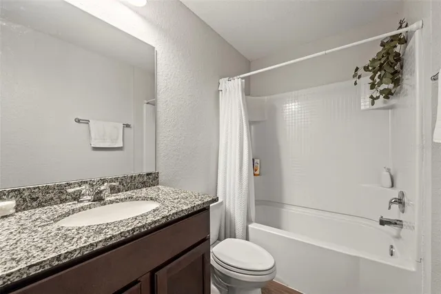 a bathroom with a granite countertop sink a toilet and shower
