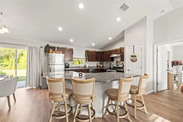 a kitchen with stainless steel appliances granite countertop a refrigerator a stove and a sink