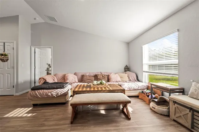 a living room with furniture and kitchen view with wooden floor