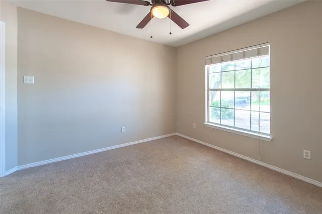 an empty room with a window and a ceiling fan