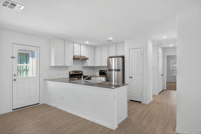 a kitchen with stainless steel appliances granite countertop a refrigerator sink and white cabinets