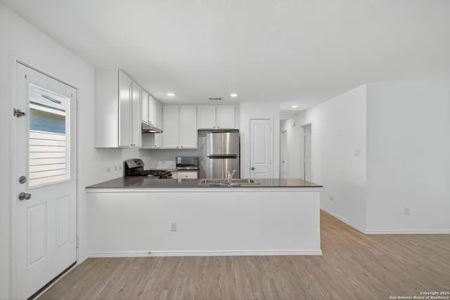 a kitchen with stainless steel appliances granite countertop a sink a stove and a refrigerator