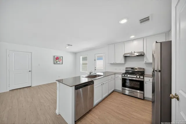 a kitchen with stainless steel appliances granite countertop a stove top oven a sink and a refrigerator