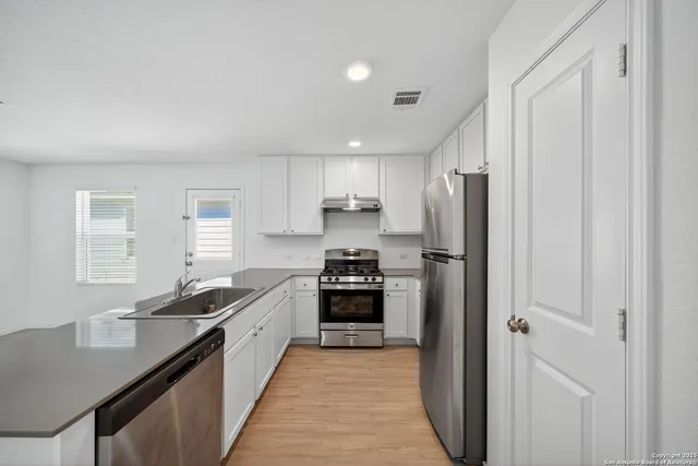 a kitchen with stainless steel appliances granite countertop a refrigerator and a stove top oven