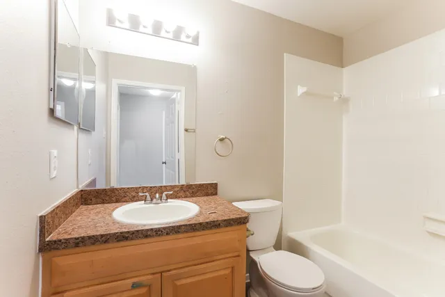 a bathroom with a granite countertop sink a toilet and a mirror
