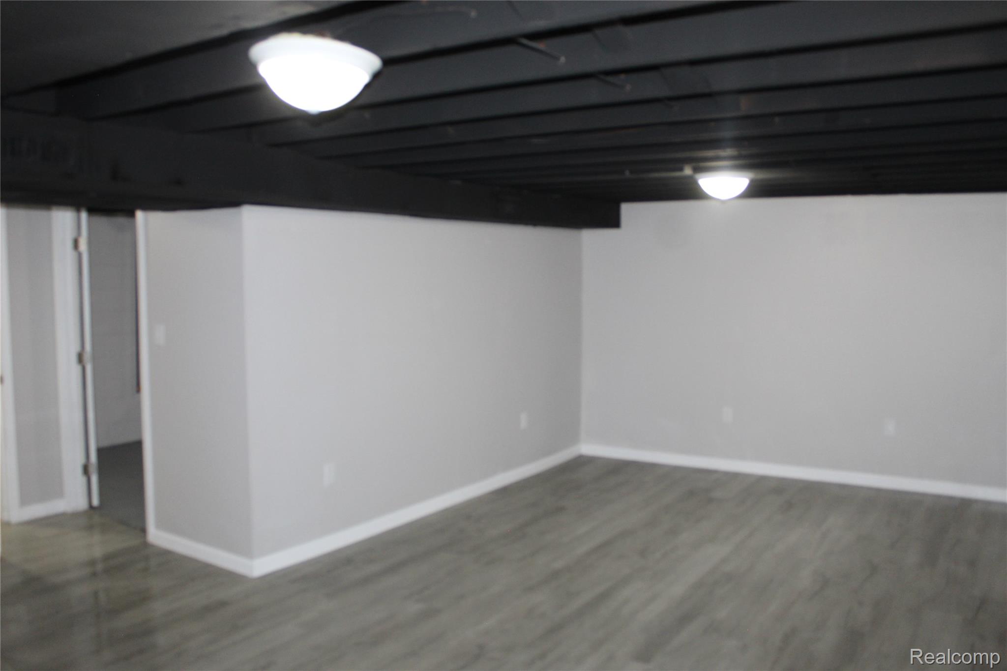 5543 Balfour Road Detroit, MI 48224 - Photo 30 of 54 Finished room featuring light gray painted walls, white baseboards, wood-finish flooring, and a painted exposed ceiling with surface-mount lighting fixtures